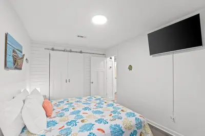 a bedroom with a bed and a flat screen tv at Spacious Dog-Friendly Unit with Game Room & Private Yard, Walk to East PCB Beach in Panama City Beach