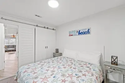 a white bedroom with a bed and a sign on the wall at Spacious Dog-Friendly Unit with Game Room & Private Yard, Walk to East PCB Beach in Panama City Beach