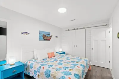 a bedroom with a bed and two blue tables at Spacious Dog-Friendly Unit with Game Room & Private Yard, Walk to East PCB Beach in Panama City Beach