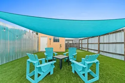 a patio with blue chairs and a table on the grass at Spacious Dog-Friendly Duplex w/ Bonus Game Room & Private Backyard Near Beach in Panama City Beach