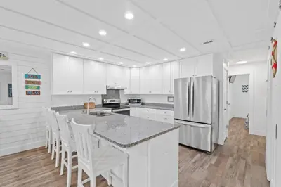 a kitchen with white cabinets and a kitchen island with white chairs at Spacious Dog-Friendly Duplex w/ Bonus Game Room & Private Backyard Near Beach in Panama City Beach