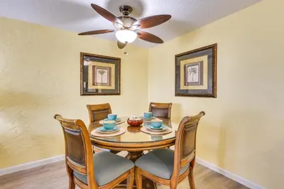 a dining room with a table with chairs and a ceiling fan at Steps to Shore PCB Condo with Pool Access and Balcony in Panama City Beach