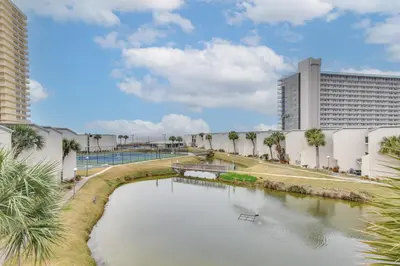 a river in front of a building with palm trees at Steps to Shore PCB Condo with Pool Access and Balcony in Panama City Beach