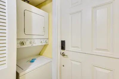 a bathroom with a washer and dryer next to a door at Steps to Shore PCB Condo with Pool Access and Balcony in Panama City Beach
