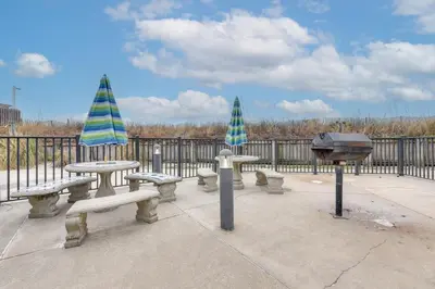 a group of picnic tables and a grill with umbrellas at Steps to Shore PCB Condo with Pool Access and Balcony in Panama City Beach