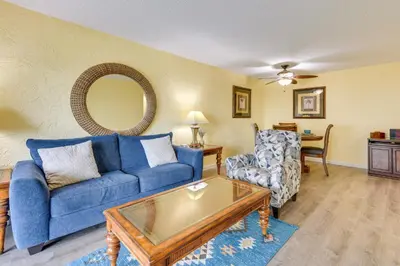 a living room with a blue couch and a chair at Steps to Shore PCB Condo with Pool Access and Balcony in Panama City Beach