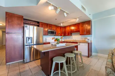 a kitchen with wooden cabinets and a island with bar stools at Laketown Wharf Condo beach view in Panama City Beach