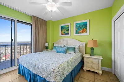 a bedroom with a bed with green walls and a window at Treasure Island #2101 in Panama City Beach