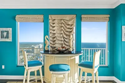 a dining room with blue walls and two chairs at Treasure Island #2101 in Panama City Beach
