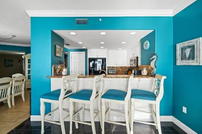 a kitchen with blue walls and a bar with chairs at Treasure Island #2101 in Panama City Beach