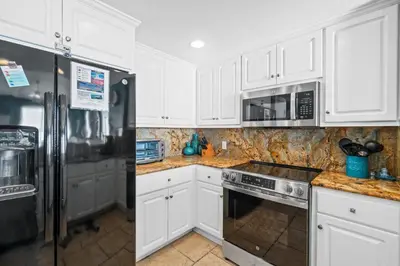 a kitchen with white cabinets and stainless steel appliances at Treasure Island #2101 in Panama City Beach