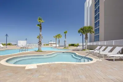 a swimming pool with chairs and palm trees in a building at Laketown Wharf 338 condo in Panama City Beach