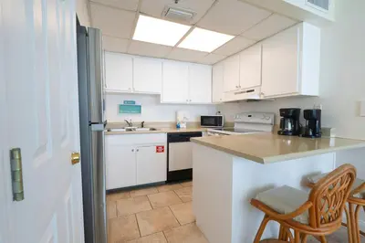 a kitchen with white cabinets and a table and chairs at Sunbird Resort 10th Floor Amazing Sunsets - by Sunbird Rentals in Panama City Beach