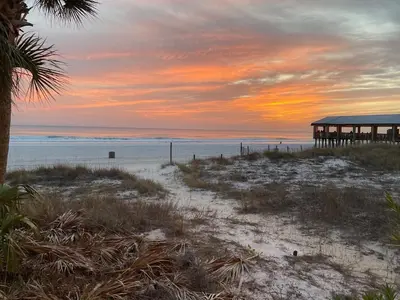 a beach with a pier and the ocean at sunset at Sunbird Resort - First Floor - Free Beach Chairs by Sunbird Rentals in Panama City Beach