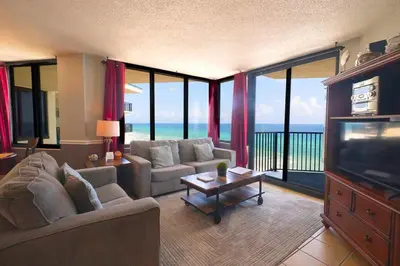 a living room with couches and a television and a balcony at Sunbird Resort 11th Floor Free Beach Chairs - by Sunbird Rentals in Panama City Beach