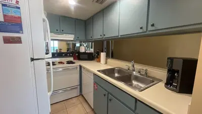 a kitchen with a sink and a refrigerator at Sunbird Resort 5th Floor Amazing View! - by Sunbird Rentals in Panama City Beach