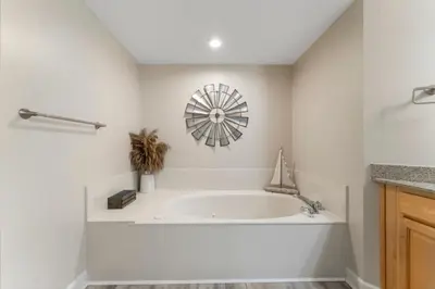 a white bathroom with a tub and a clock on the wall at Gulf-Front Corner Unit! Stunning Coastline Views! by Dolce Vita Getaways PCB in Panama City Beach