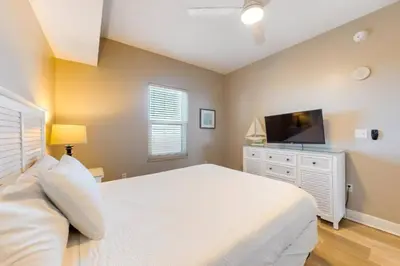 a bedroom with a white bed and a flat screen tv at 21st-Floor Sunrise Beach Gulf-Front Condo w/ Bunks & Panoramic Views in Panama City Beach