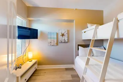 a bedroom with two bunk beds and a tv at 21st-Floor Sunrise Beach Gulf-Front Condo w/ Bunks & Panoramic Views in Panama City Beach