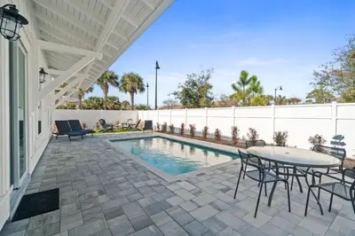a patio with a table and chairs next to a pool at New 6BR Home Sleeps 20 | Private Pool, Walk to Beach, Near Pier Park in Panama City Beach