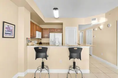 a kitchen with two black stools at a counter at Sunrise Beach 14th-Floor Gulf-Front Condo w/ Pools, Bunks & Balcony Views in Panama City Beach
