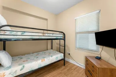 a bedroom with two bunk beds and a flat screen tv at Sunrise Beach 14th-Floor Gulf-Front Condo w/ Pools, Bunks & Balcony Views in Panama City Beach