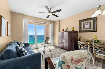 a living room with a blue couch and a ceiling fan at Sunrise Beach 14th-Floor Gulf-Front Condo w/ Pools, Bunks & Balcony Views in Panama City Beach