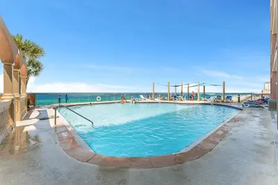 a large swimming pool with the ocean in the background at Sunrise Beach 14th-Floor Gulf-Front Condo w/ Pools, Bunks & Balcony Views in Panama City Beach