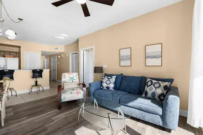 a living room with a blue couch and a table at Sunrise Beach 14th-Floor Gulf-Front Condo w/ Pools, Bunks & Balcony Views in Panama City Beach