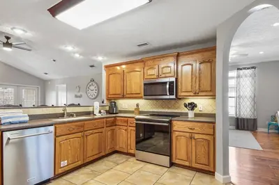a kitchen with wooden cabinets and stainless steel appliances at Large Pet-Friendly Beach Home | Sleeps 14 Near Pier Park in Panama City Beach