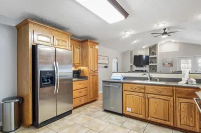 a kitchen with wooden cabinets and a stainless steel refrigerator at Large Pet-Friendly Beach Home | Sleeps 14 Near Pier Park in Panama City Beach