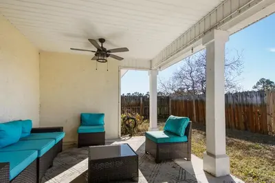 a patio with two blue chairs and a ceiling fan at Large Pet-Friendly Beach Home | Sleeps 14 Near Pier Park in Panama City Beach