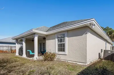a white house with a blue chair in the yard at Large Pet-Friendly Beach Home | Sleeps 14 Near Pier Park in Panama City Beach