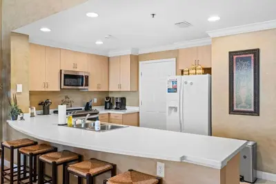 a kitchen with a large white counter and stools at Sunrise Beach 14th-Floor Gulf-Front Condo Pools, Bunks & Balcony Views in Panama City Beach