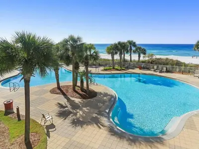 a large swimming pool with palm trees and the beach at Sunrise Beach 14th-Floor Gulf-Front Condo Pools, Bunks & Balcony Views in Panama City Beach