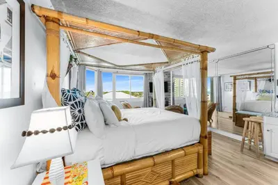 a bedroom with a canopy bed and a desk with a lamp at Top of the Gulf 620 Beachfront Couples Retreat in Panama City Beach