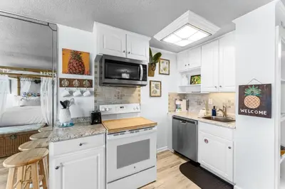 a kitchen with white cabinets and a sink at Top of the Gulf 620 Beachfront Couples Retreat in Panama City Beach