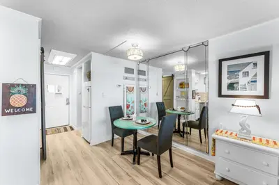 a dining room with a table and chairs and a mirror at Top of the Gulf 620 Beachfront Couples Retreat in Panama City Beach
