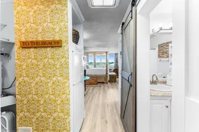 a hallway with a yellow wall with a sign that reads to the beach at Top of the Gulf 620 Beachfront Couples Retreat in Panama City Beach