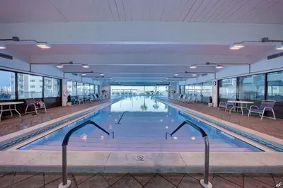 a swimming pool with tables and chairs in a building at Stunning condo in Pinnacle Port, Panama City Beach in Panama City Beach