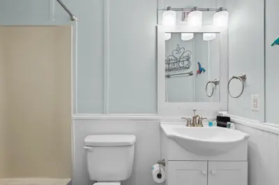 a white bathroom with a toilet and a sink at SeaRenity Awaits: 2-BD, 2-BA Coastal Escape! Perfect for 5! Pet Friendly! in Laguna Beach