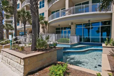 a villa with a swimming pool in front of a building at Aqua Beach Resort by Panhandle Getaways in Panama City Beach