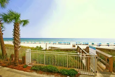 a view of a beach with a fence and a beach with umbrellas at Aqua Beach Resort by Panhandle Getaways in Panama City Beach