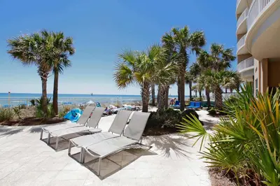 a row of lounge chairs on the beach with palm trees at Aqua Beach Resort by Panhandle Getaways in Panama City Beach