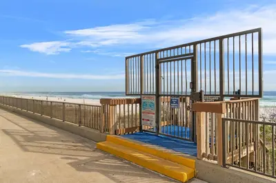 a gate on the side of a beach at AquaVista Beach Resort by Panhandle Getaways in Panama City Beach