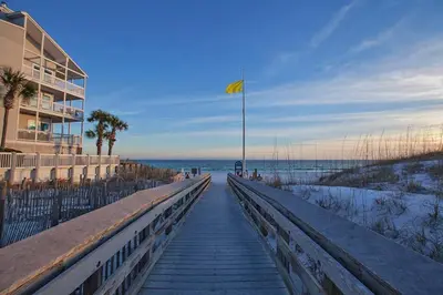 a boardwalk leading to a beach with a yellow flag at Beachside Villas by Panhandle Getaways in Seagrove Beach