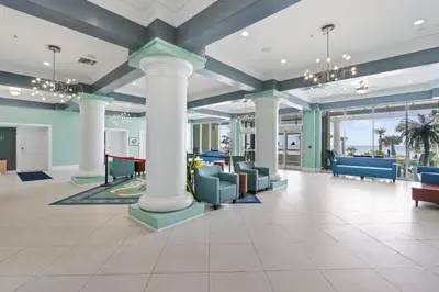 a large lobby with columns and chairs and windows at Boardwalk Beach Resort by Panhandle Getaways in Panama City Beach