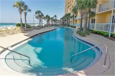 a swimming pool at a resort with palm trees and a building at Calypso Resort by Panhandle Getaways in Panama City Beach