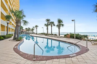 a swimming pool with palm trees and the ocean at Calypso Resort by Panhandle Getaways in Panama City Beach
