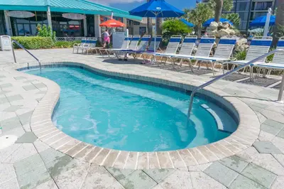 a swimming pool with chairs and an umbrella at Edgewater Beach & Golf Resort by Panhandle Getaways in Panama City Beach